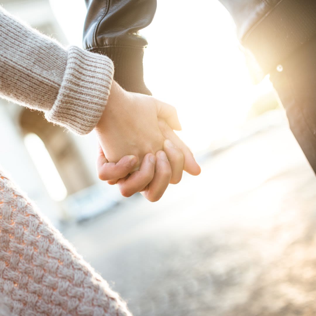 Junges Paar geht Hand in Hand im Sonnenlicht und teilt gemeinsame Werte für eine langfristige Beziehung.