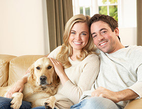 Zwei liebende mit Hund sitzen glücklich auf der Couch
