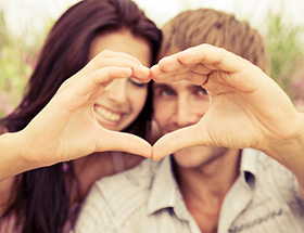 Ein glückliches Paar formt gemeinsam ein Herz mit Ihren Händen.