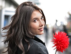 Partnerwahl Zürich: Eine brunette Frau hält eine rote Blume.