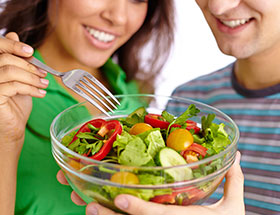 Single-Frau und Single-Mann teilen sich einen vegetarischen Salat