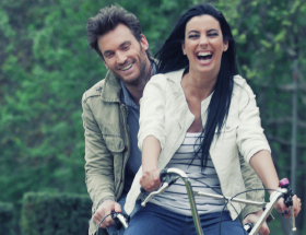 Zwei Verliebte teilen sich lachend ein Fahrrad
